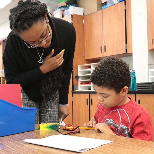  A student intern works with a young student